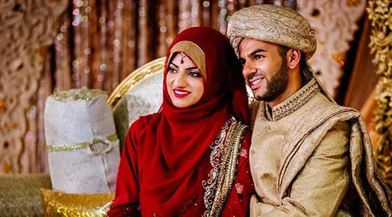 Couple seated together in red and gold wedding outfits