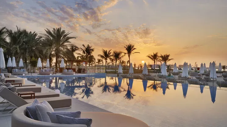 Palm trees and a resort swimming pool at sunset